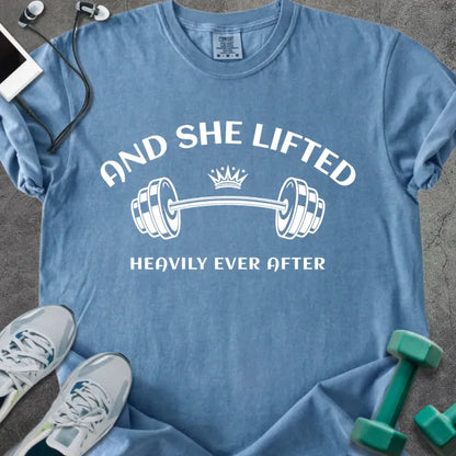 Blue jean t-shirt printed with "And She Lifted Heavily Ever After" in white, with a barbell and crown