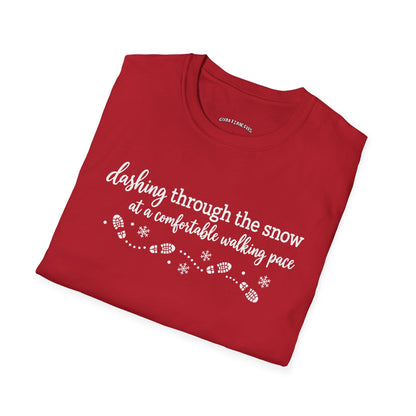 Folded cherry red t-shirt printed with "dashing through the snow at a comfortable walking pace" in white, with a dotted trail of footprints and snowflakes