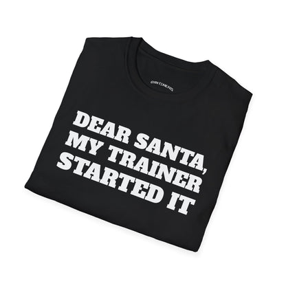 Folded black t-shirt printed with "DEAR SANTA, MY TRAINER STARTED IT" in white