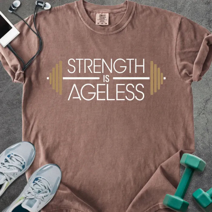 Espresso t-shirt printed with "Strength is Ageless" in white and gold, with a barbell graphic