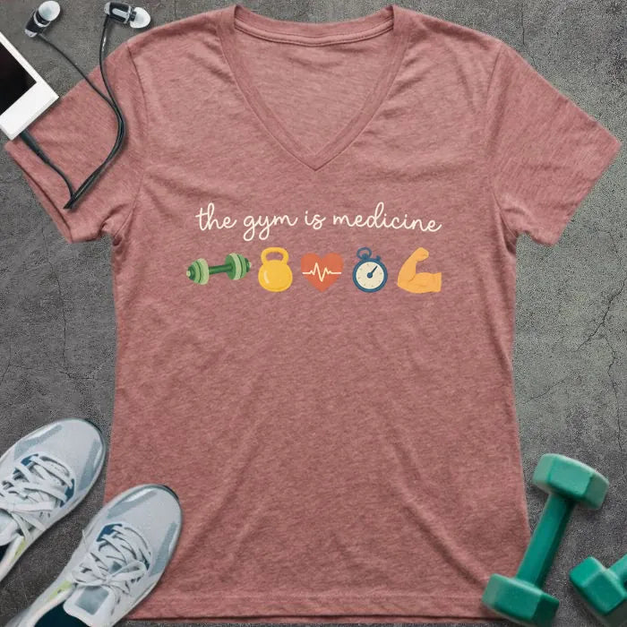 Heather mauve t-shirt printed with "the gym is medicine" in yellow and orange, with dumbbell, kettlebell, heartbeat, weight scale, clock, and bicep graphics