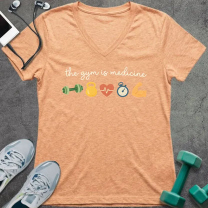 Heather peach t-shirt printed with "the gym is medicine" in yellow and orange, with dumbbell, kettlebell, heartbeat, weight scale, clock, and bicep graphics