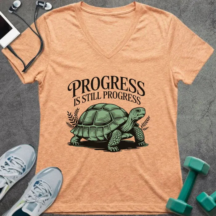 Heather peach t-shirt printed with "Progress is Still Progress" in green, with a turtle