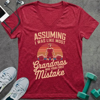 Heather red t-shirt printed with "ASSUMING I WAS LIKE MOST Grandmas WAS YOUR FIRST Mistake" in cream, orange, red, black, with a muscular woman silhouette deadlifting over a retro sunset
