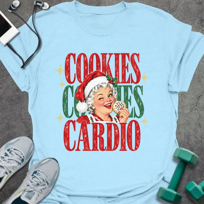 Light blue t-shirt printed with "COOKIES COOKIES CARDIO" in red and green, with a vintage Mrs. Claus in a Santa hat winking and holding a frosted cookie