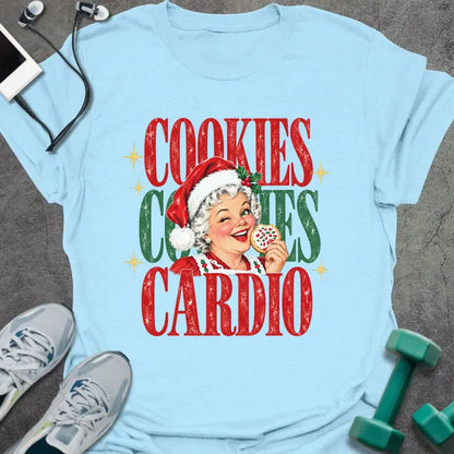 Light blue t-shirt printed with "COOKIES COOKIES CARDIO" in red and green, with a vintage Mrs. Claus in a Santa hat winking and holding a frosted cookie
