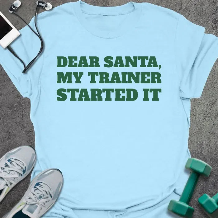 Light blue t-shirt printed with "DEAR SANTA, MY TRAINER STARTED IT" in green