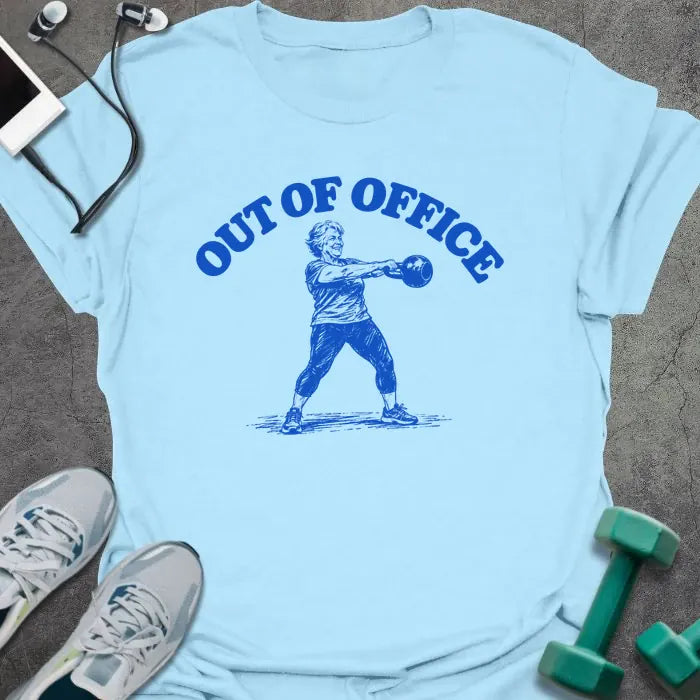 Light blue t-shirt printed with "OUT OF OFFICE" in blue, with a sketch of an older woman swinging a kettlebell