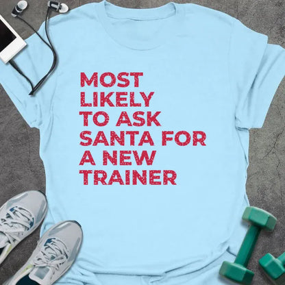 Light blue t-shirt printed with "MOST LIKELY TO ASK SANTA FOR A NEW TRAINER" in red