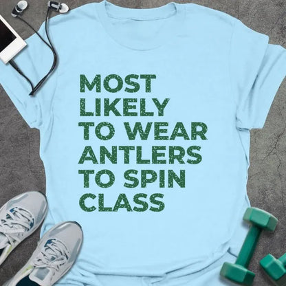 Light blue t-shirt printed with "MOST LIKELY TO WEAR ANTLERS TO SPIN CLASS" in green