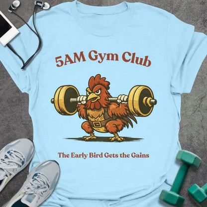 Light blue t-shirt printed with "5AM Gym Club The Early Bird Gets the Gains" in red and brown, with rooster lifting barbell graphic