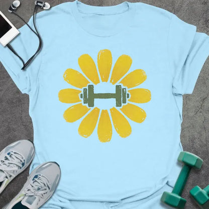 Light blue t-shirt with an illustration of a dandelion flower surrounding a dumbbell in yellow and green