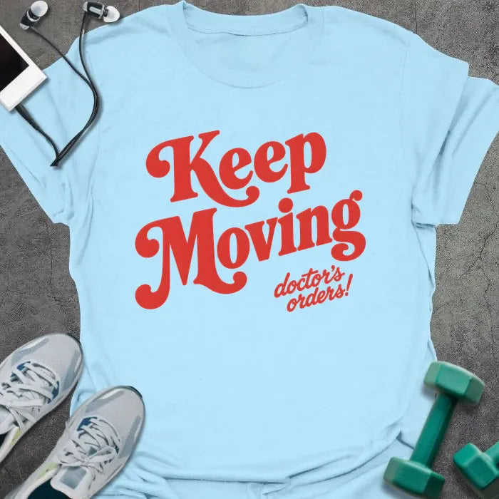 Light Blue t-shirt printed with "Keep Moving doctor's orders!" in red script lettering
