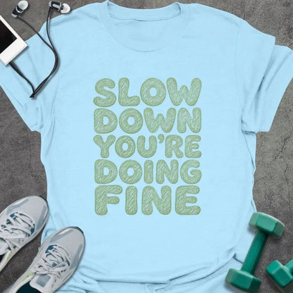 Light blue t-shirt printed with "SLOW DOWN YOU'RE DOING FINE" in green