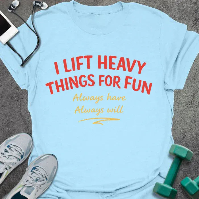 Light blue t-shirt printed with "I LIFT HEAVY THINGS FOR FUN Always have. Always will." in black, with a retro illustration of a woman lifting a barbell