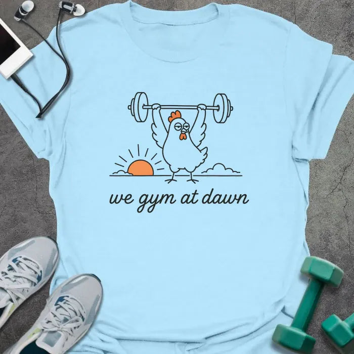 Light blue t-shirt printed with "we gym at dawn" in orange, with a bird lifting weights at sunrise