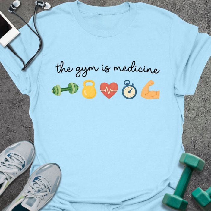 Light blue t-shirt printed with "the gym is medicine" in multicolor, with emoji icons of gym equipment