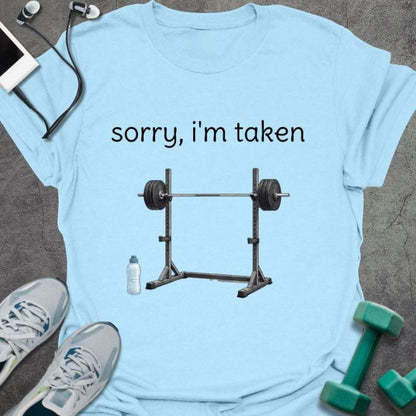 Light blue t-shirt printed with "sorry, i'm taken", with a barbell with weights