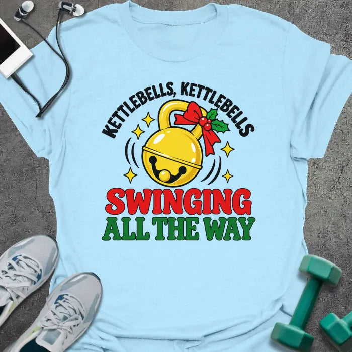 Light blue t-shirt printed with "KETTLEBELLS, KETTLEBELLS, SWINGING ALL THE WAY" in black, red and green, with a gold jingle bell kettlebell and holly