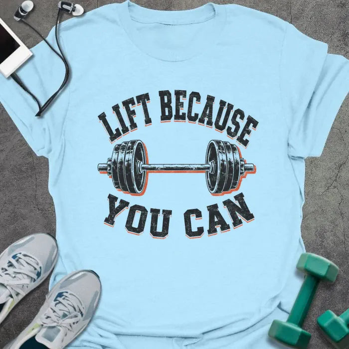 Light Blue t-shirt printed with "LIFT BECAUSE YOU CAN" in black and red text with a barbell graphic
