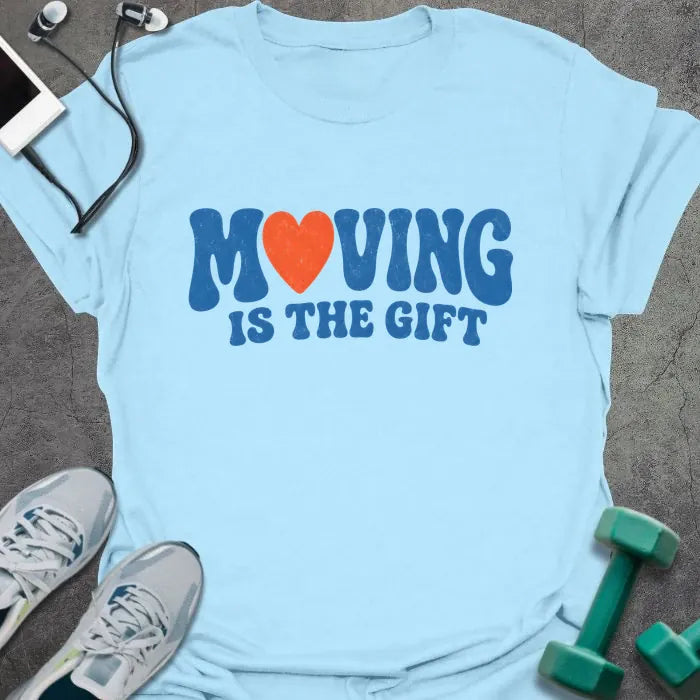 Light Blue t-shirt printed with "MOVING IS THE GIFT" in blue and orange text with a heart replacing the O