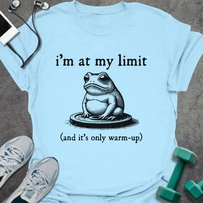 Light blue t-shirt printed with "i'm at my limit (and it's only warm-up)" in black, with an illustration of a frog sitting