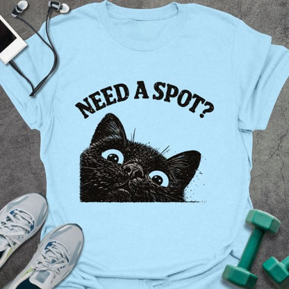 Light blue t-shirt printed with "Need a Spot?" in black, with an illustration of a cat's face looking up