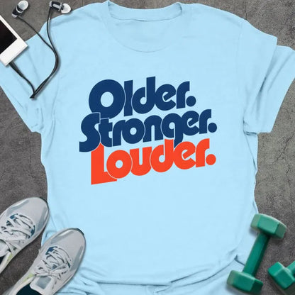 Light Blue t-shirt printed with "Older. Stronger. Louder." in navy blue with orange bold lettering