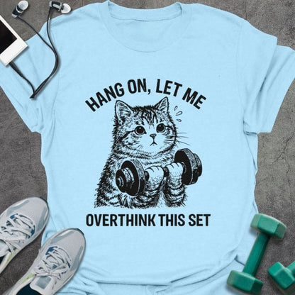Light blue t-shirt printed with "Hang on, Let Me Overthink This Set", with a cat holding dumbbells