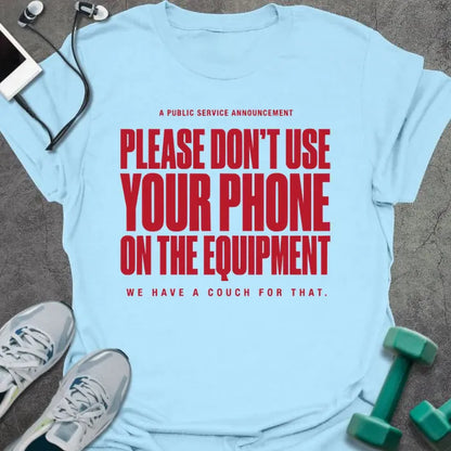 Light blue t-shirt printed with "A Public Service Announcement Please Don't Use Your Phone on the Equipment We Have a Couch for That." in red