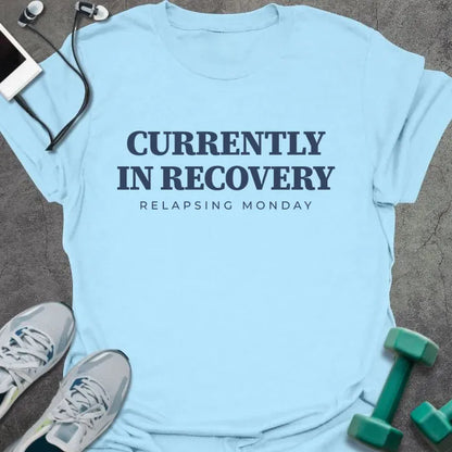 Light blue t-shirt printed with "CURRENTLY IN RECOVERY, RELAPSING MONDAY" in navy blue
