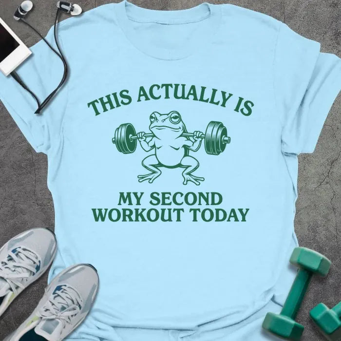 Light blue t-shirt printed with "This Actually is my Second Workout Today" in green, with an illustration of a frog lifting barbell