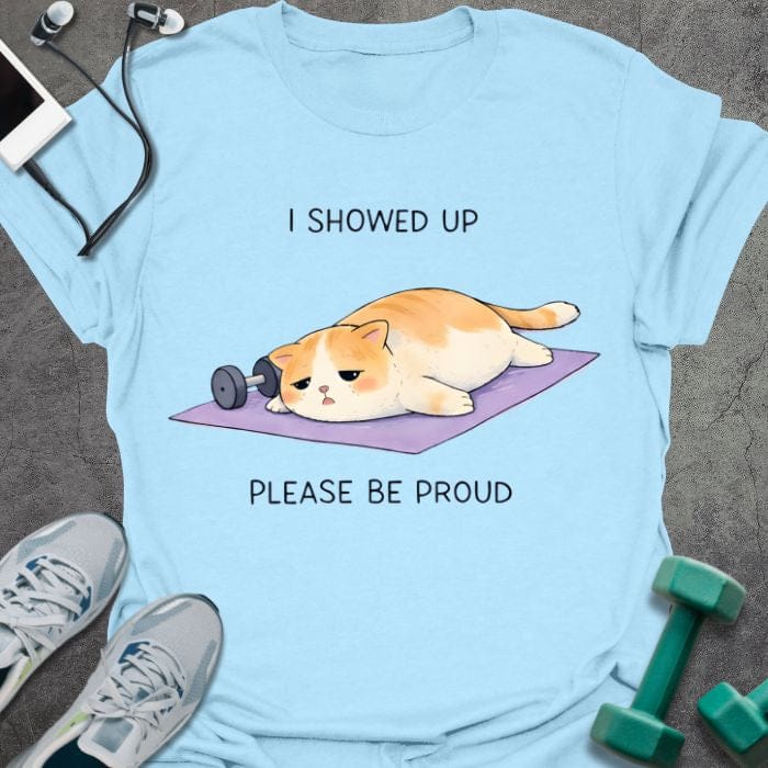 Light blue t-shirt printed with "I Showed Up Please Be Proud" in orange, white, purple, with an orange and white cat on a purple yoga mat