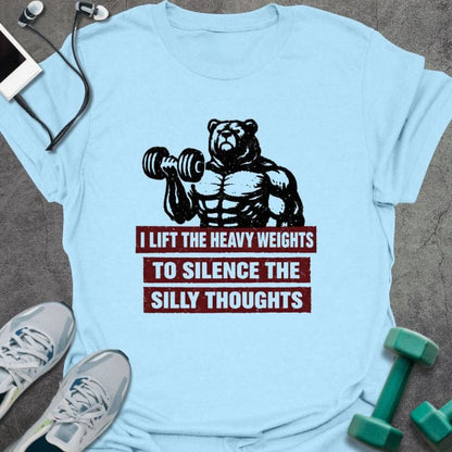 Light blue t-shirt printed with "I Lift the Heavy Weights to Silence the Silly Thoughts" in red and black, with muscular bear lifting dumbbell