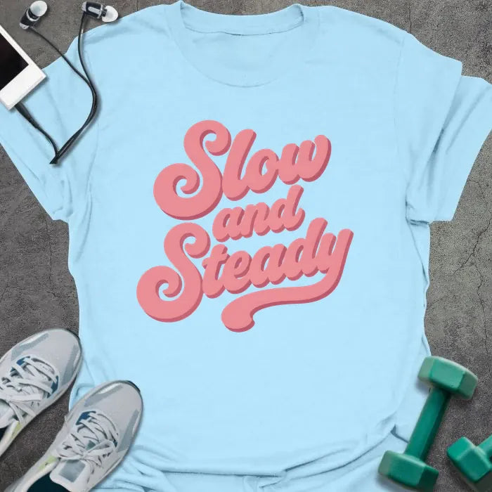 Light blue t-shirt printed with "Slow and Steady" in rose and pink
