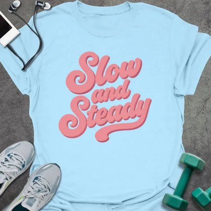 Light blue t-shirt printed with "Slow and Steady" in rose and pink