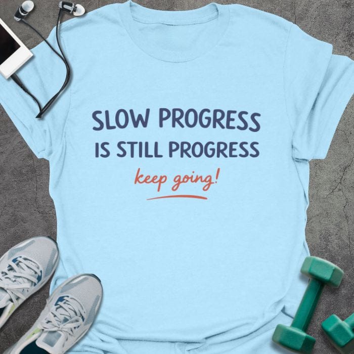 Light blue t-shirt printed with "SLOW PROGRESS IS STILL PROGRESS keep going!" in red