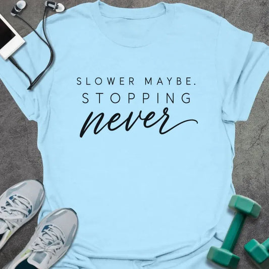 Light Blue t-shirt printed with "SLOWER MAYBE. STOPPING never" in black spaced caps with italic script