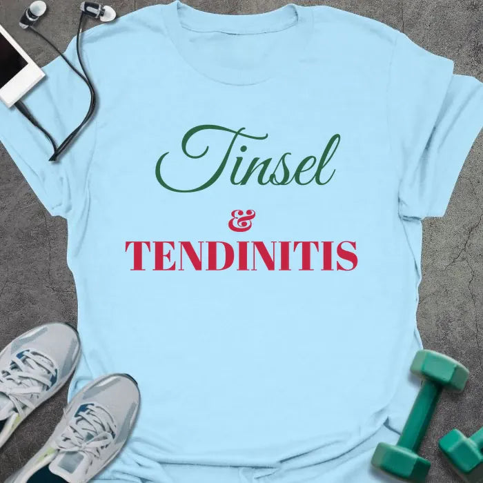 Light blue t-shirt printed with "Tinsel & Tendinitis" in green and red