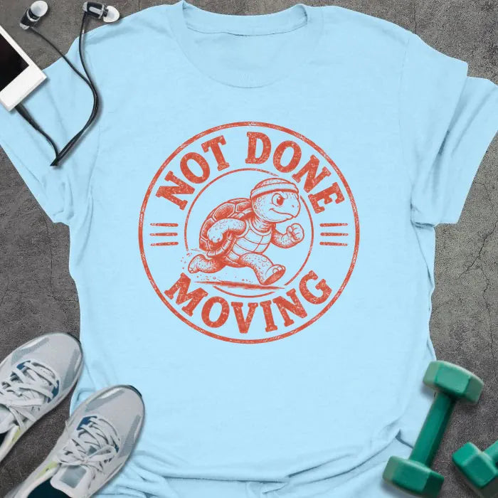 Light Blue t-shirt printed with "NOT DONE MOVING" in coral, with running turtle in circle