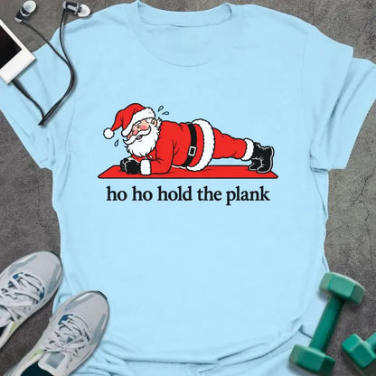 Light blue t-shirt printed with "ho ho hold the plank" in black, with Santa holding a plank on a red mat