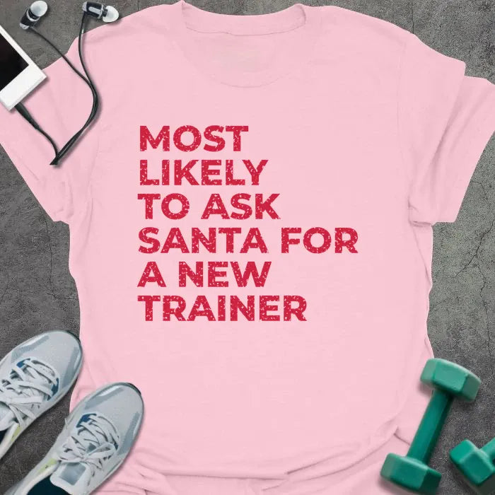 Light pink t-shirt printed with "MOST LIKELY TO ASK SANTA FOR A NEW TRAINER" in red