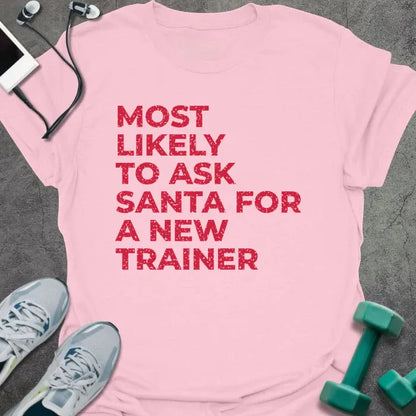 Light pink t-shirt printed with "MOST LIKELY TO ASK SANTA FOR A NEW TRAINER" in red