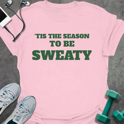 Light pink t-shirt printed with "'TIS THE SEASON TO BE SWEATY" in green