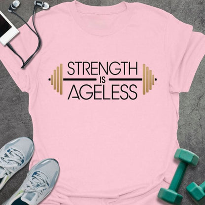 Light pink t-shirt printed with "Strength is Ageless" in yellow and blue, with barbell illustration