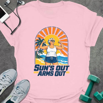Light pink t-shirt printed with "SUN'S OUT ARMS OUT" in navy blue, with a retro beach sunset and an older woman flexing her arms