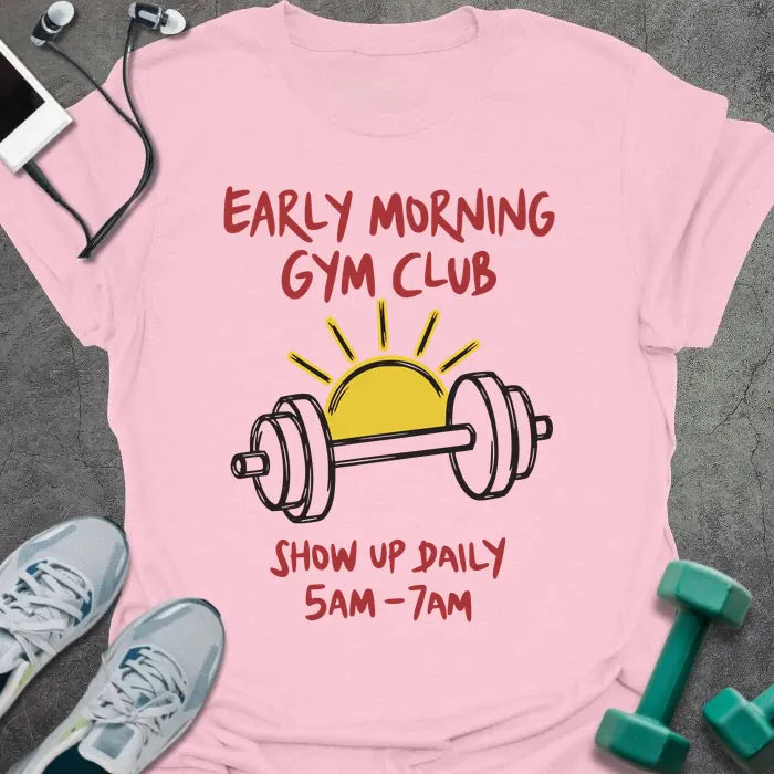 Light pink t-shirt printed with "Early Morning Gym Club Show Up Daily 5AM-7AM" in red, yellow, and black, with a yellow sun and black dumbbell illustration
