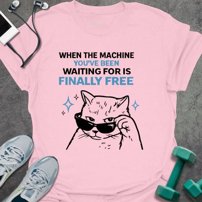 Light pink t-shirt printed with "When the Machine You've Been Waiting for is Finally Free" in black, with an illustration of a cat wearing sunglasses