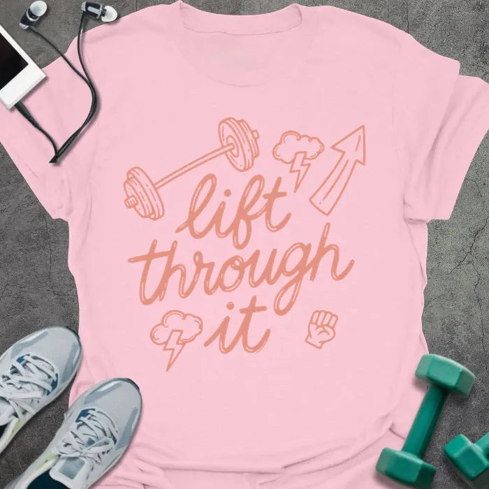 Light pink t-shirt printed with "lift through it" in orange, with dumbbell, arrow up, fist graphics