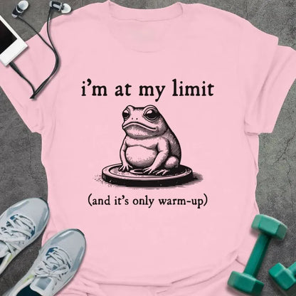 Light pink t-shirt printed with "i'm at my limit (and it's only warm-up)" in black, with an illustration of a frog sitting